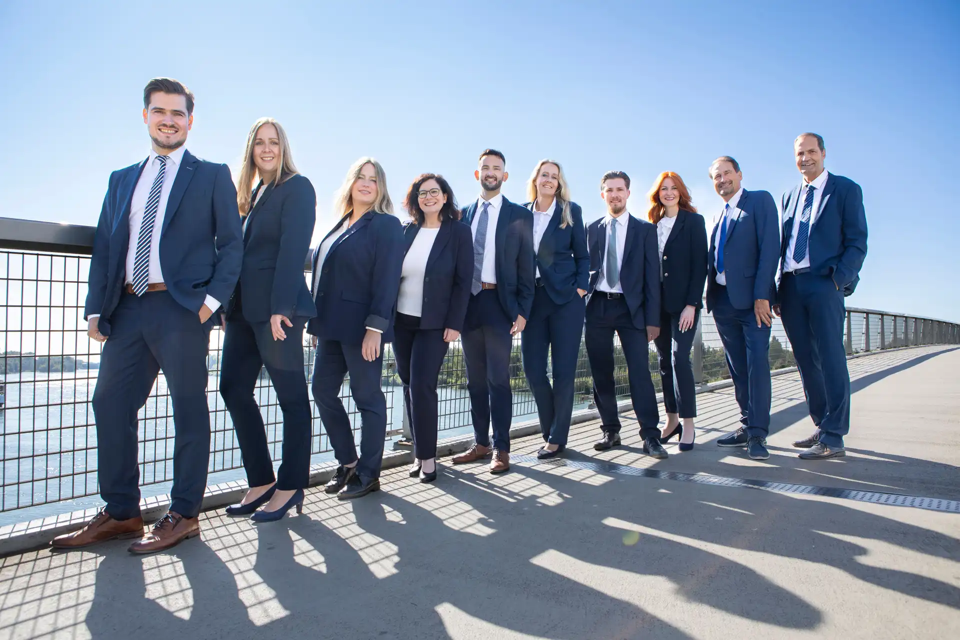 Professionelles Team aus 10 Immobilienmakler steht auf der Passerelle Brück in Kehl